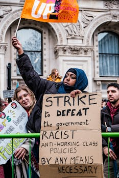 Group of protesters holding signs and flags outside an ornate historic building, advocating for social change.