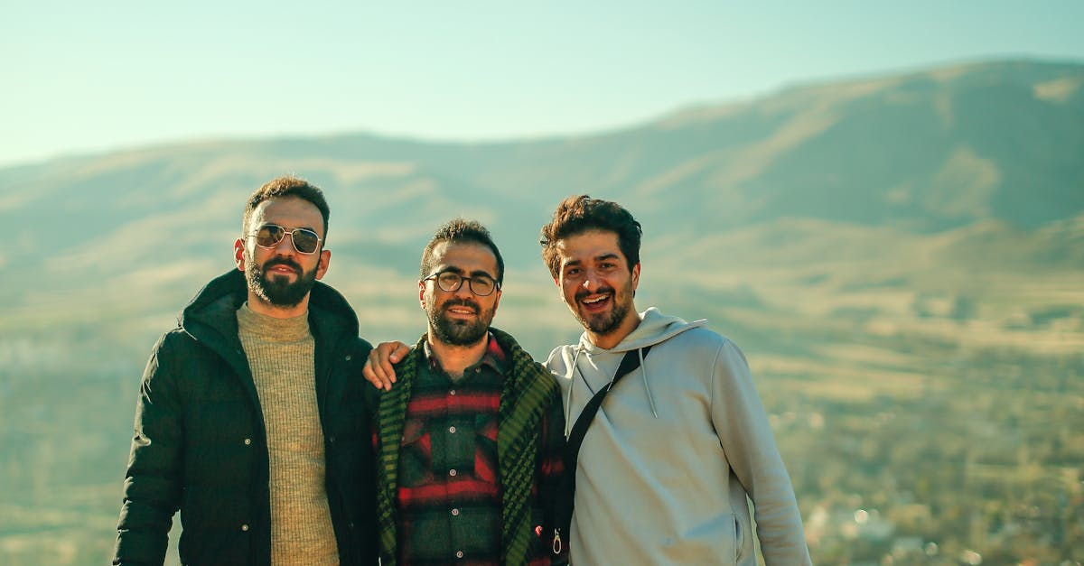 Three men smiling and posing on a scenic rooftop with a hillside backdrop.